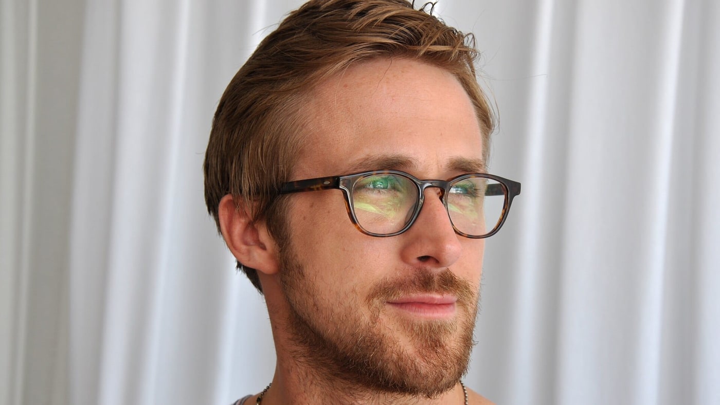 Ryan Gosling de perfil usando óculos de grau e camiseta regata