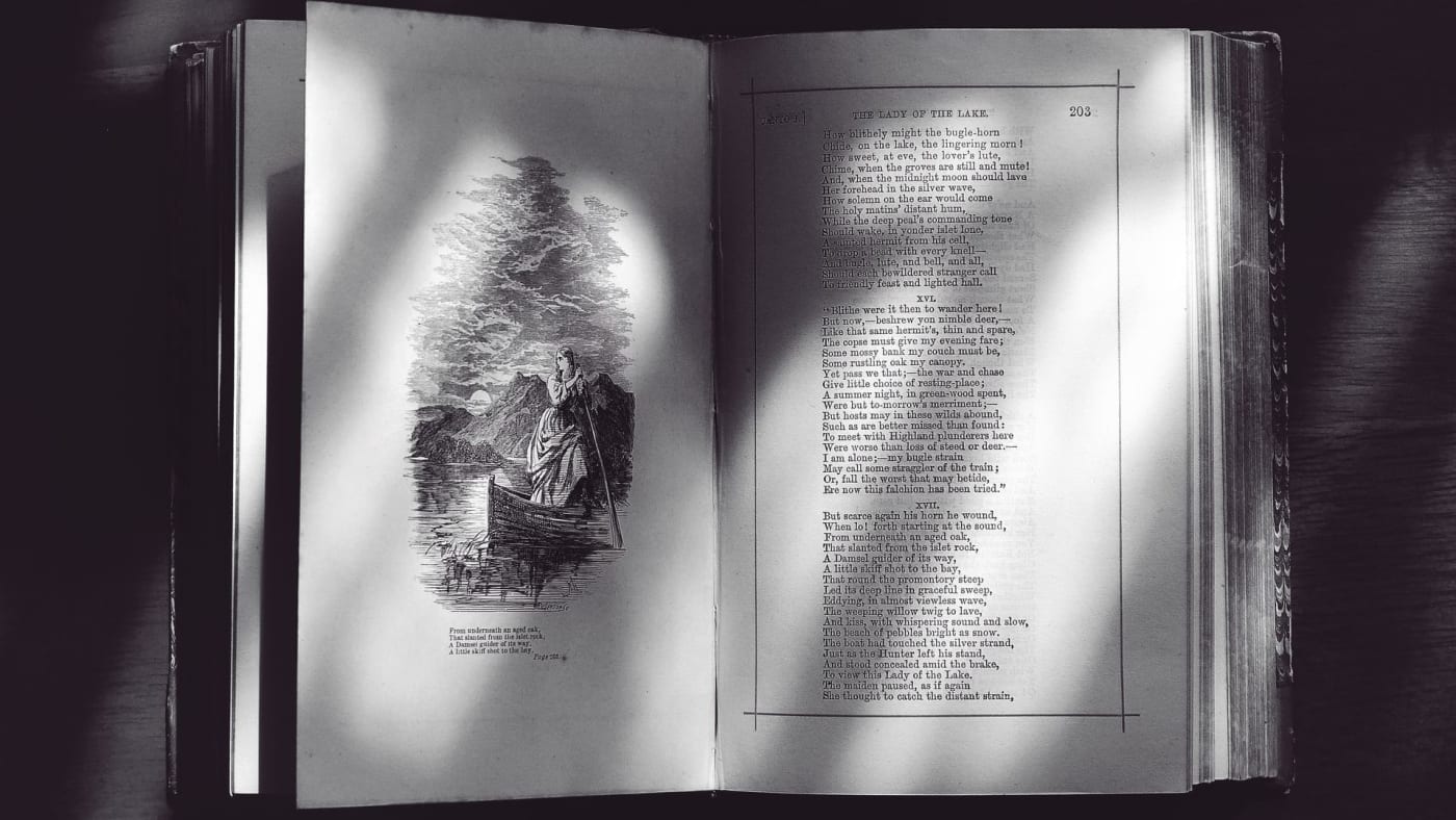 Livro antigo aberto em preto e branco, exibindo versos e uma gravura ilustrada.