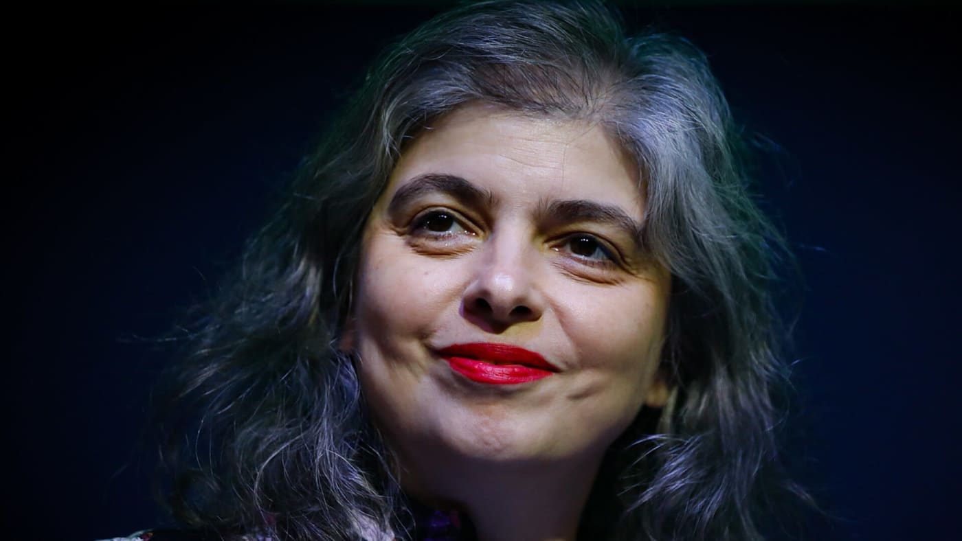 Mariana Enríquez sorri e olha para cima em close-up