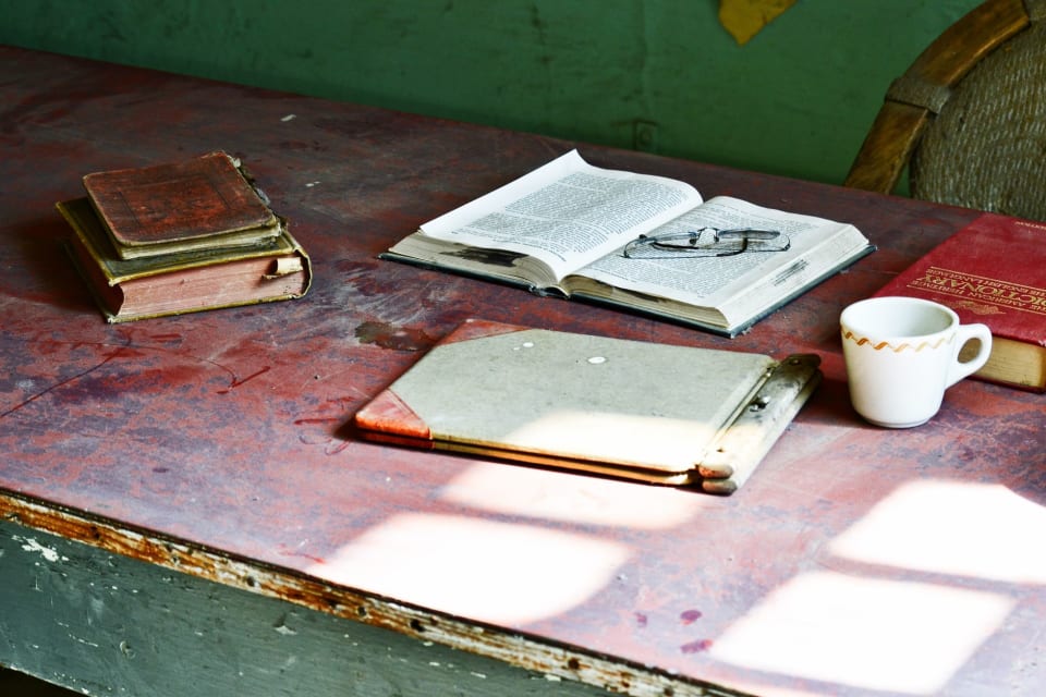 Livro aberto sobre uma mesa de trabalho, com um bloco de notas ao lado