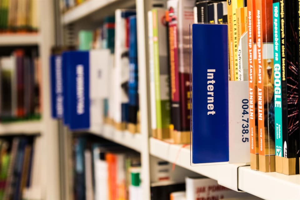Estante de biblioteca com fileiras de livros de lombadas variadas.
