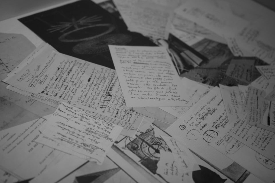 Caderno de notas manuscrito antigo, aberto, com letra à mão e rasuras.