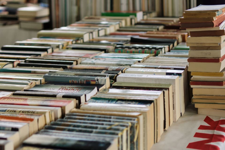 Pilhas de livros sobre uma mesa de livraria.