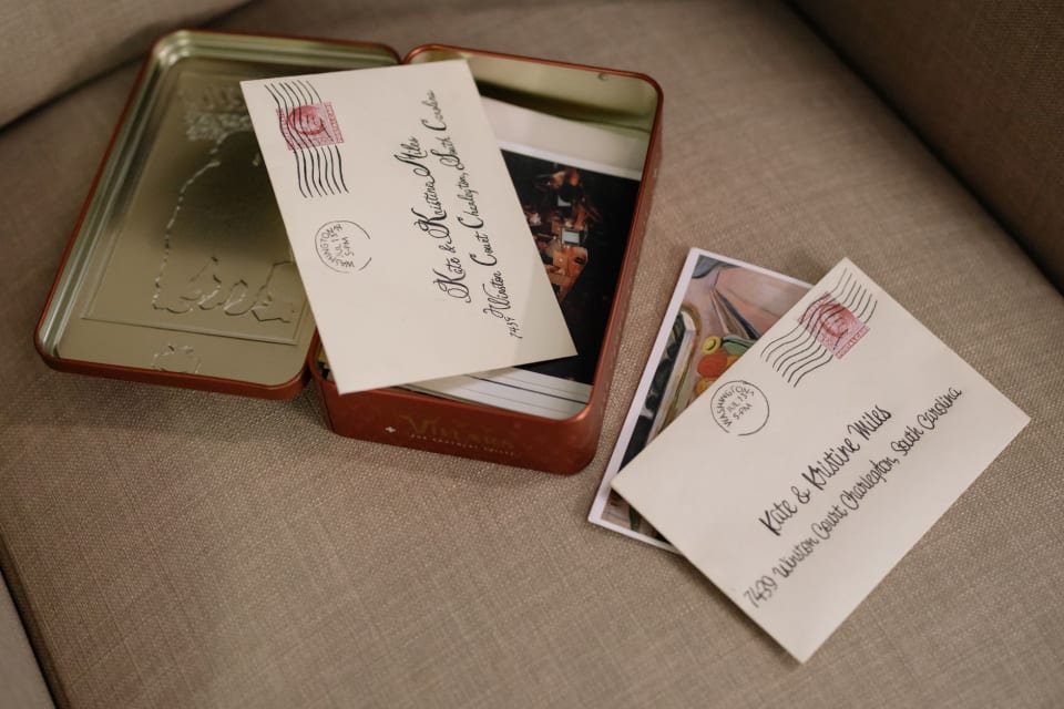 Lata aberta com envelopes escritos à mão e fotografias guardadas dentro e ao lado dela.