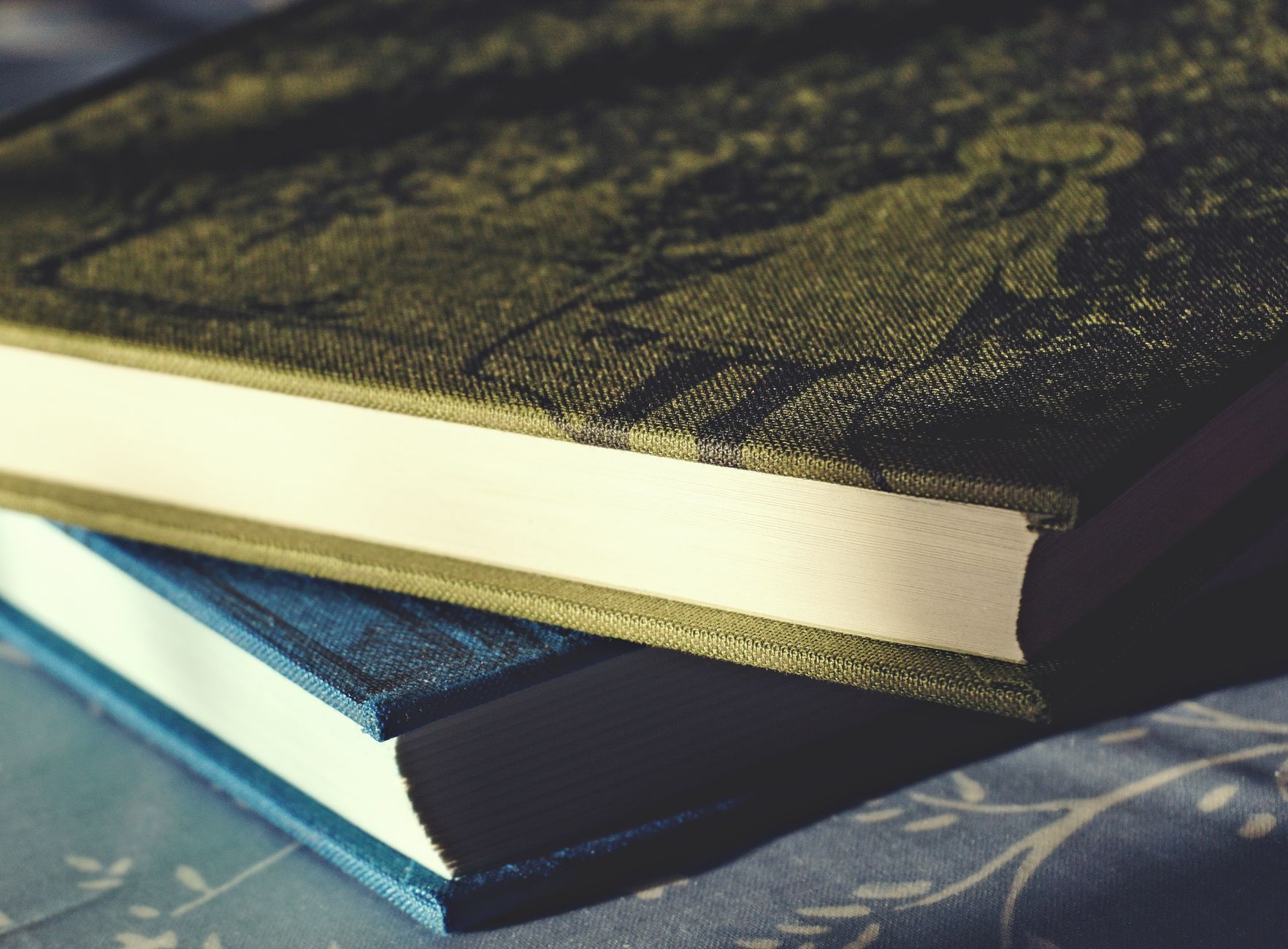 Detalhe de um livro de capa dura fechado, com o revestimento de tecido e a lombada flexível