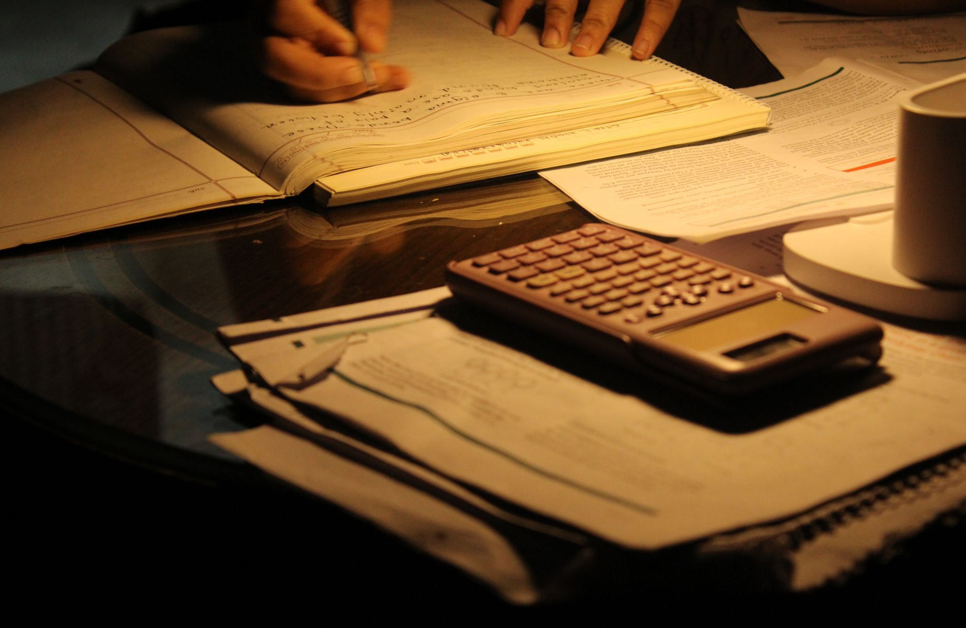caderno aberto com contas escritas à mão ao lado de uma calculadora