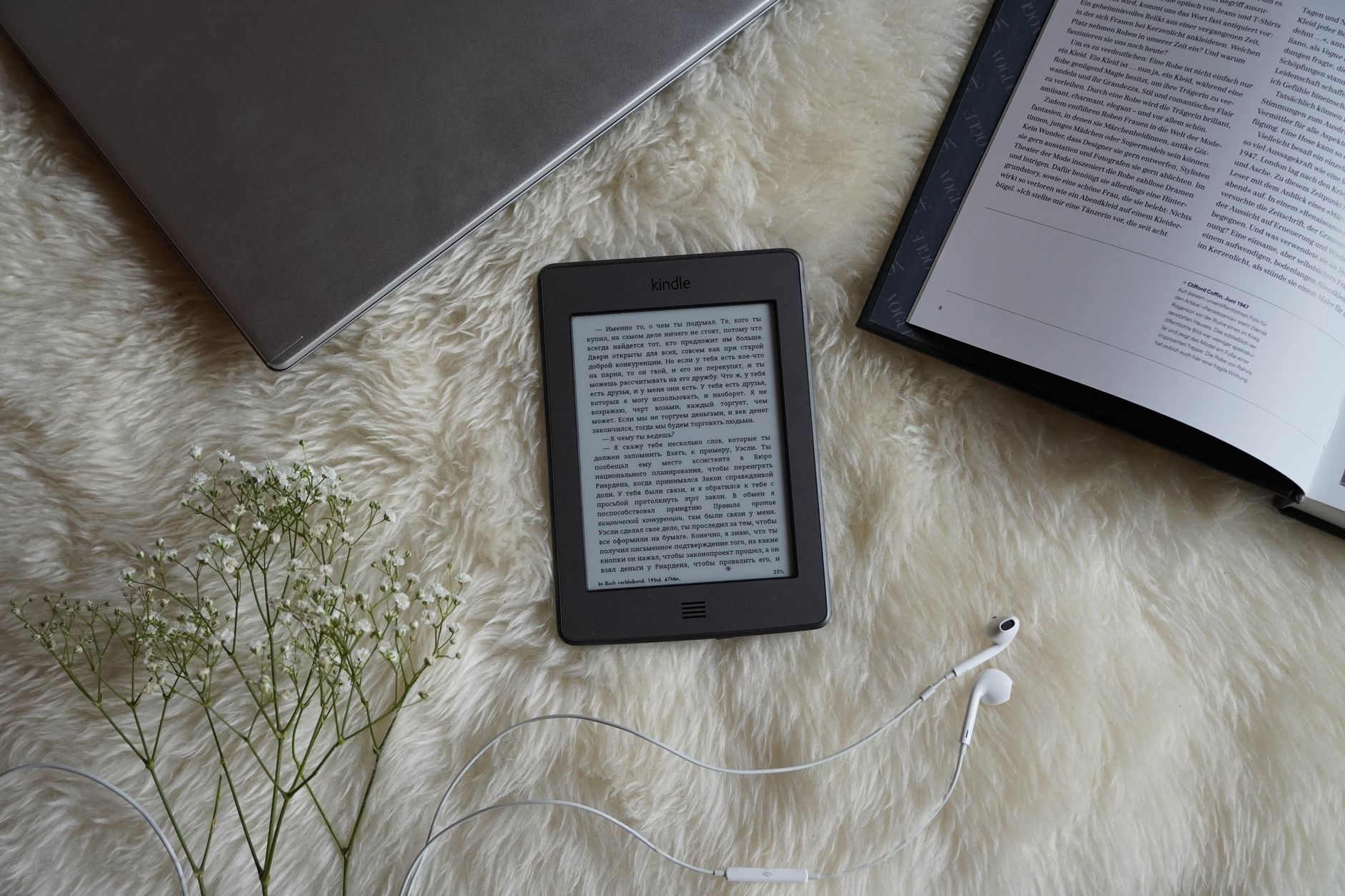 Leitor de e-book ao lado de um livro impresso sobre uma mesa
