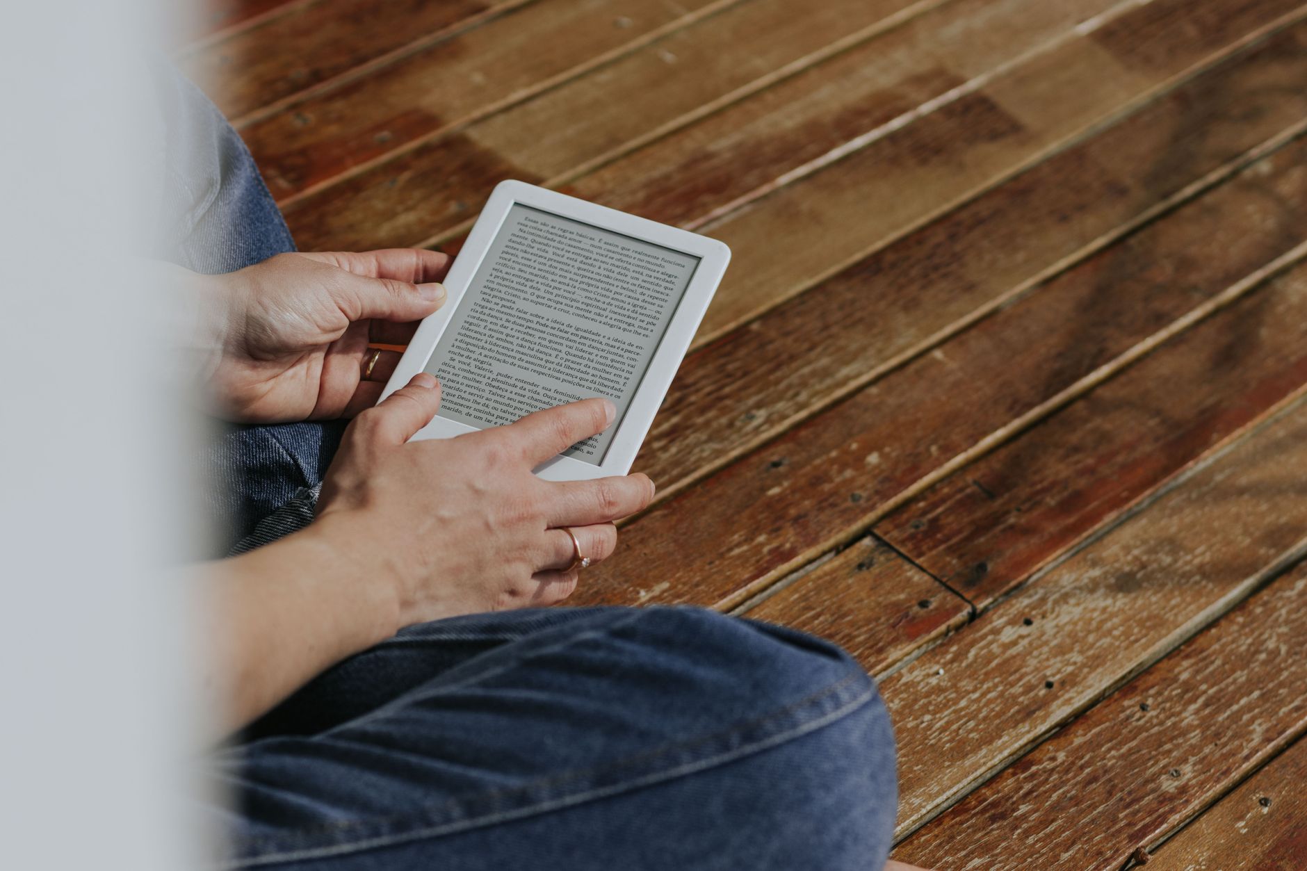 Mãos segurando um aparelho com um livro digital aberto na tela
