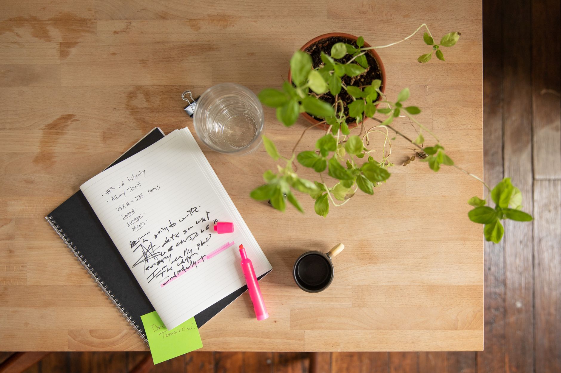 Caderno de anotações com rabiscos e frases soltas ao lado de uma xícara sobre a mesa