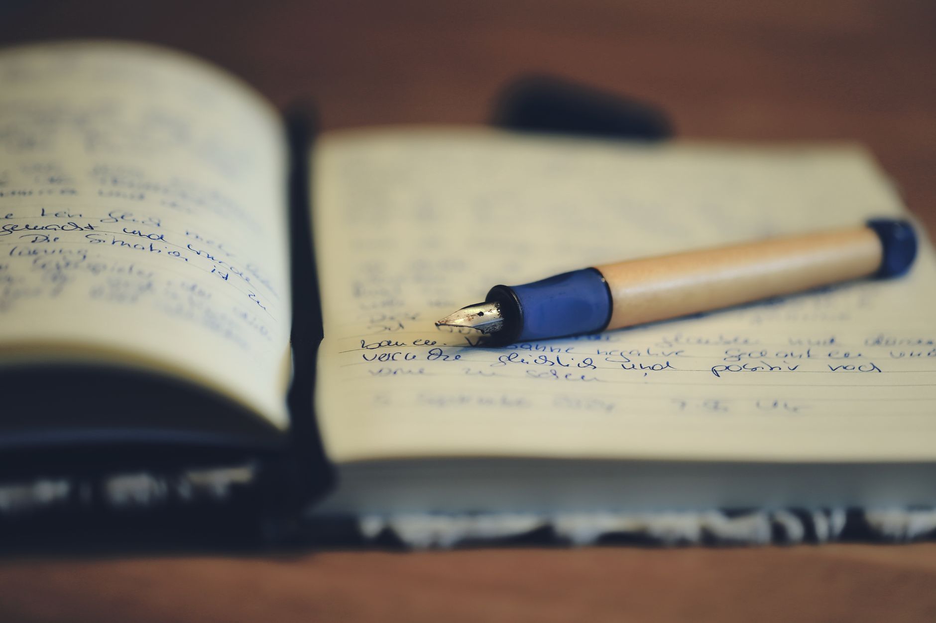 Caneta-tinteiro apoiada sobre um caderno aberto, com as páginas cheias de texto escrito à mão
