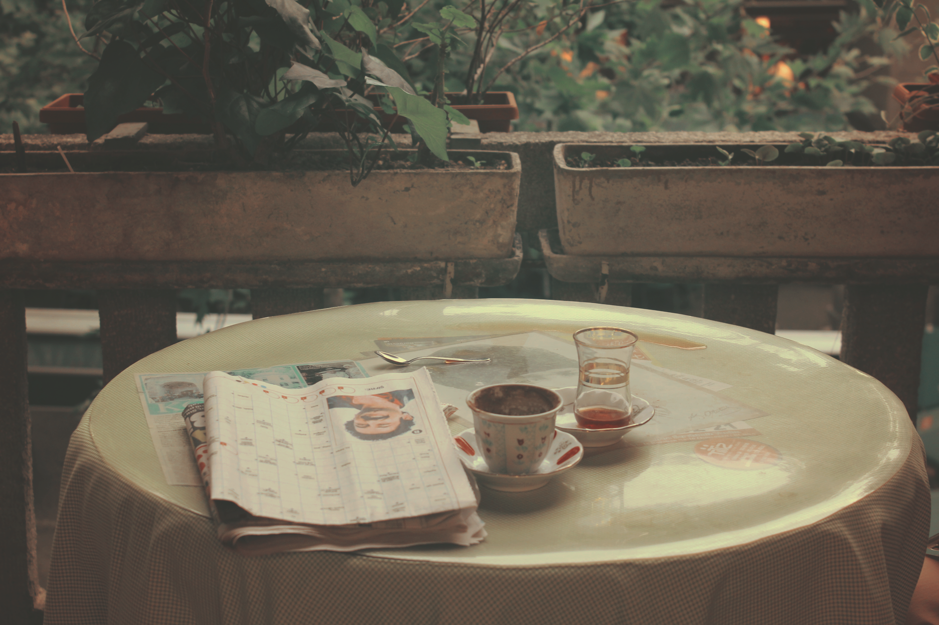 Jornal impresso dobrado sobre a mesa de um café, ao lado de uma xícara.