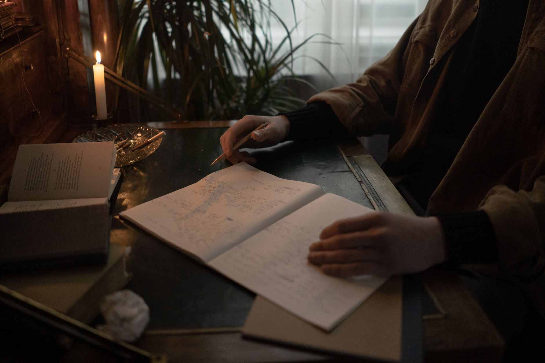 livro aberto ao lado de um caderno e uma caneta sobre uma mesa