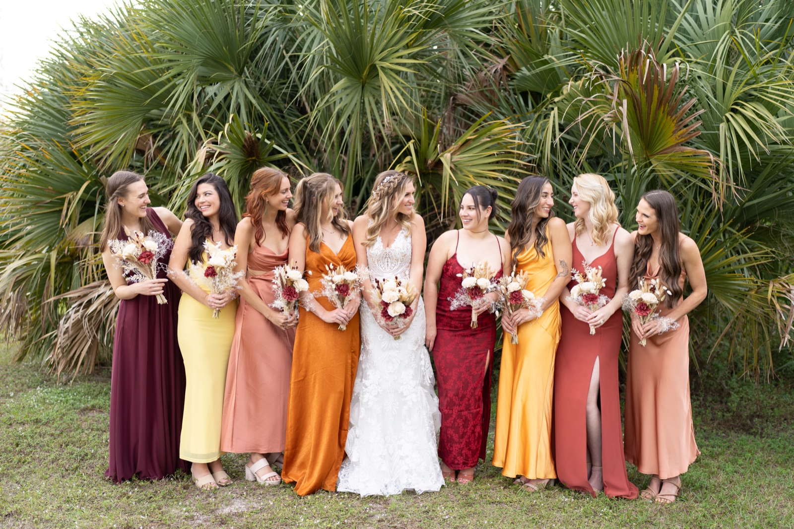 Eight bridesmaids in mismatched autumn-toned dresses with dried flower bouquets and bride at Misty Morning Barn wedding
