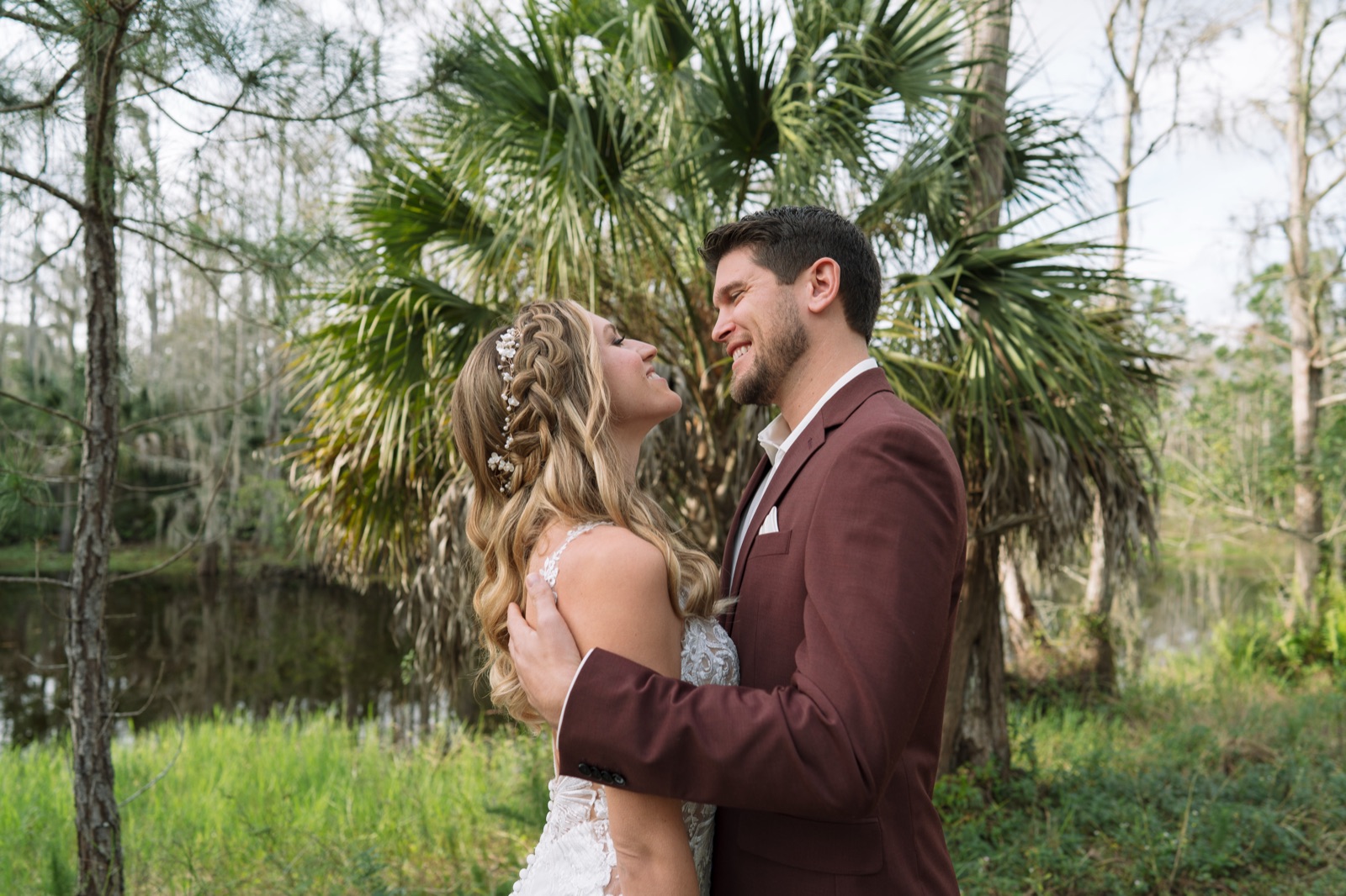 Kelli and Bradley laughing together by the pond with sabal palms and Spanish moss at Misty Morning Barn, Fort Myers Florida