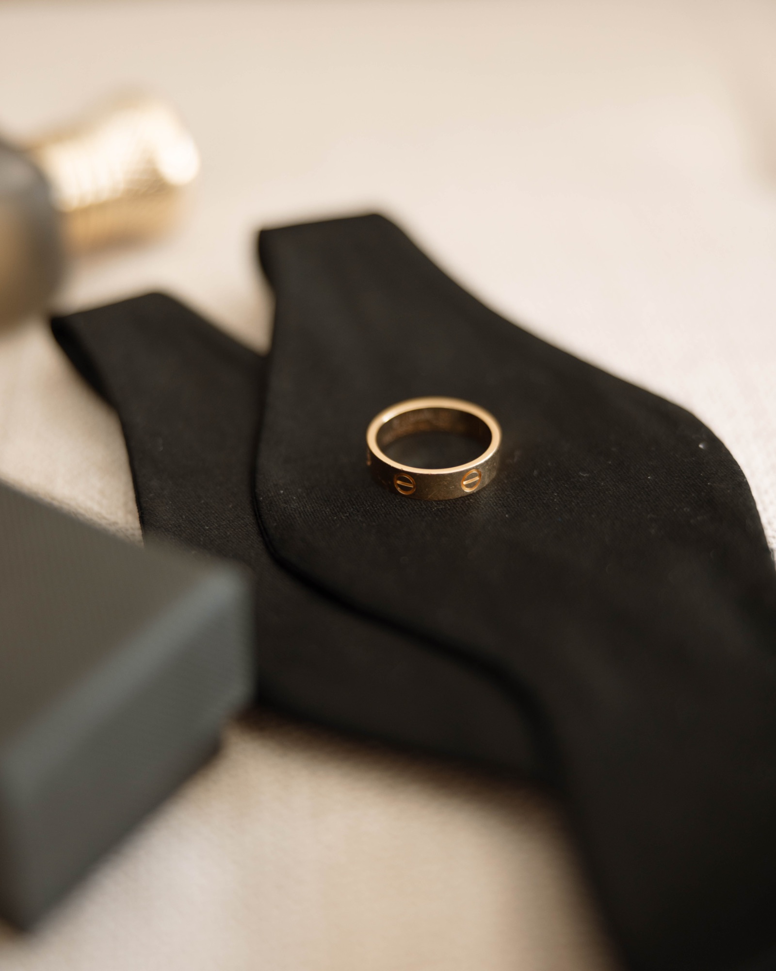 The wedding band resting on the groom's folded bow tie
