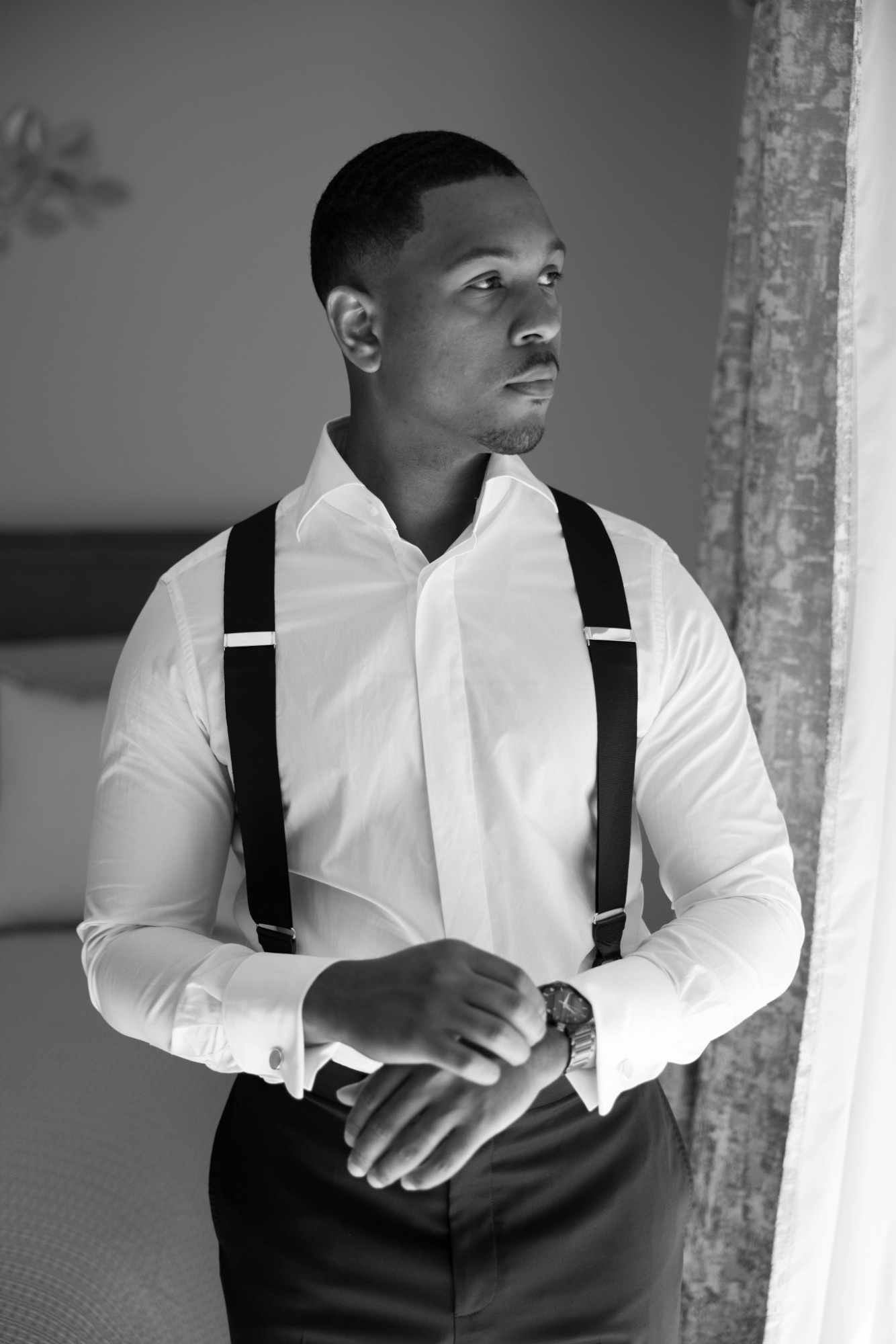 Black and white portrait of the groom by the window before the ceremony