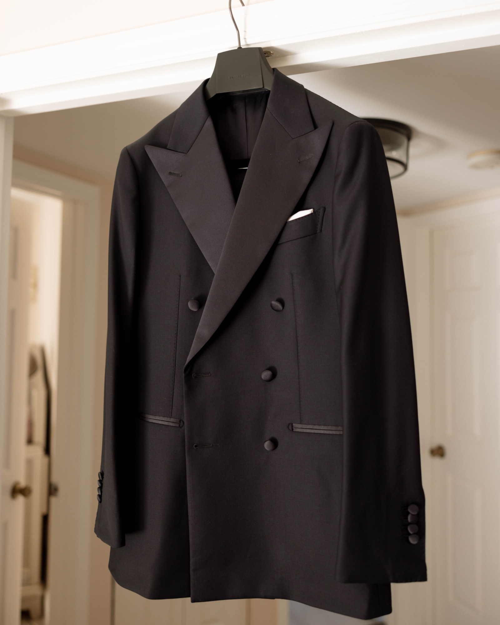 The groom's double-breasted tuxedo hanging in the suite