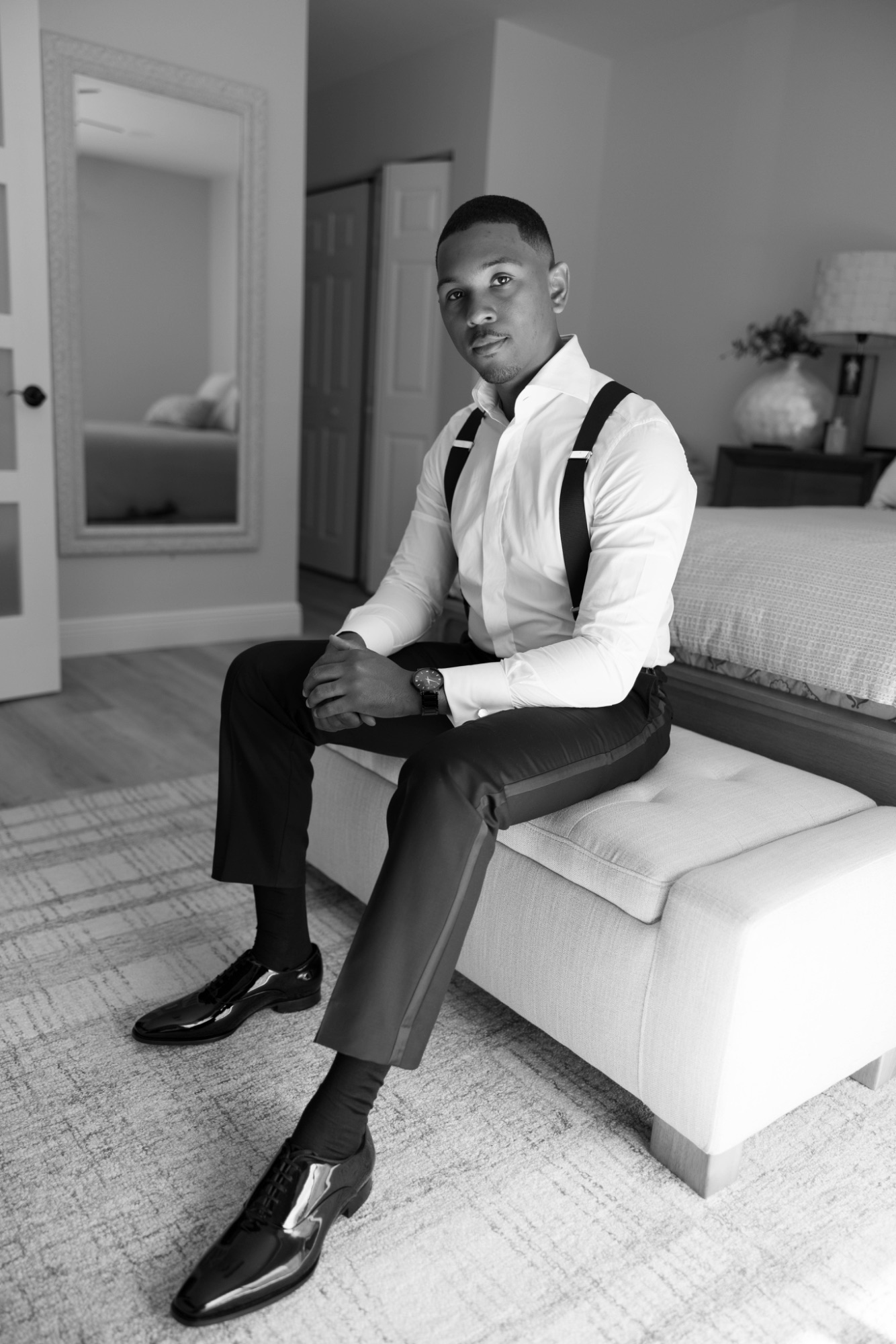 The groom seated at the end of the bed, dressed and waiting