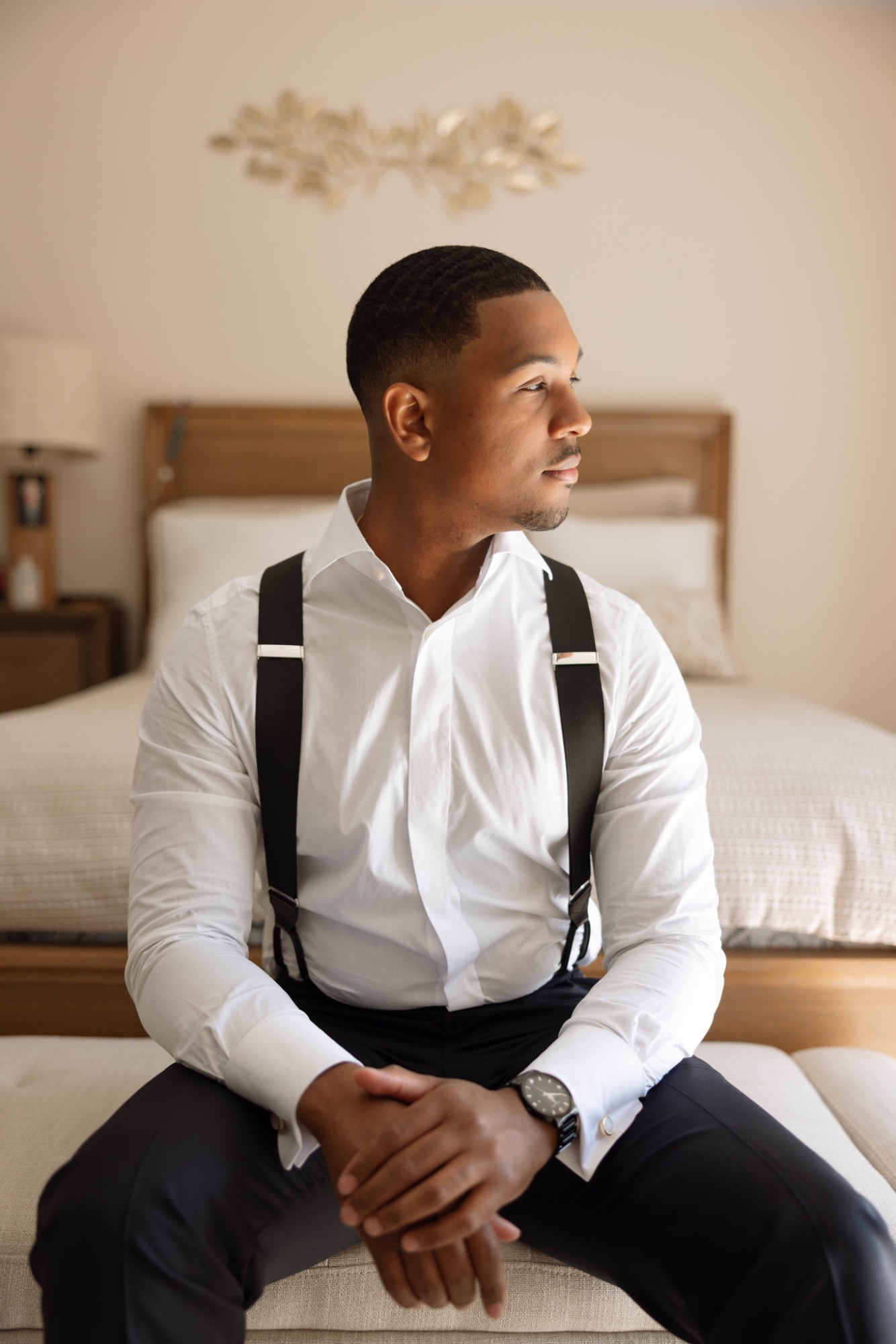 The groom sitting in suspenders before the tuxedo goes on