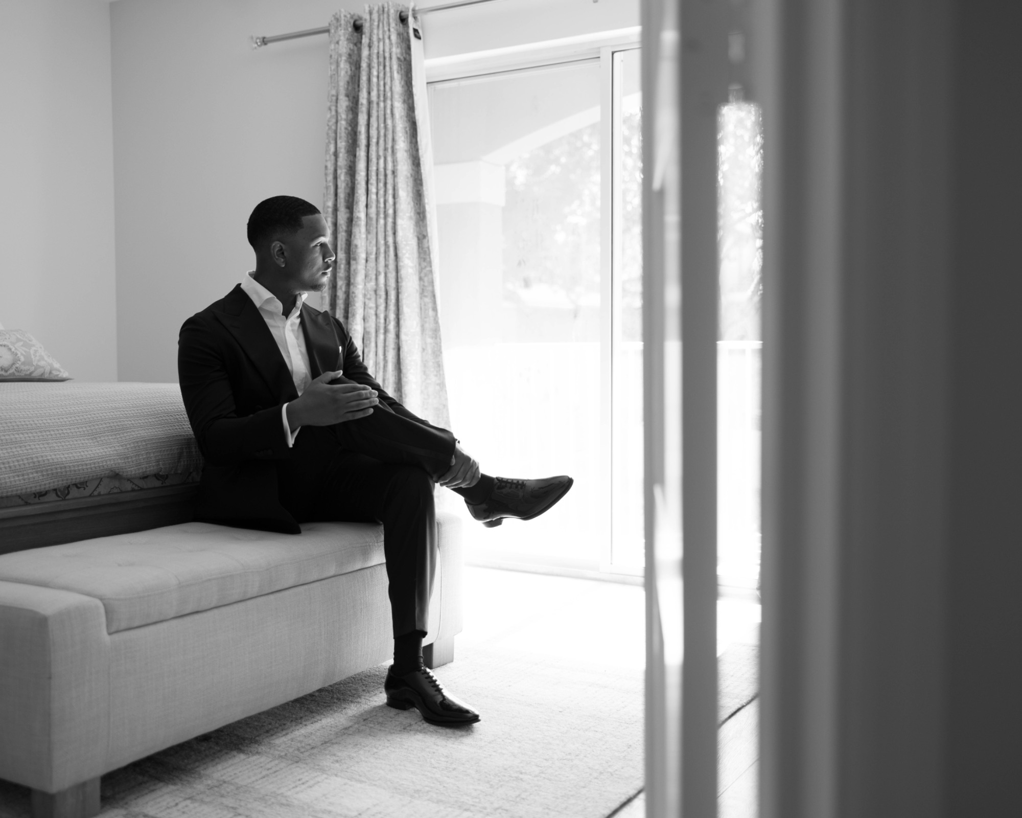 The groom in the window light before leaving for the church