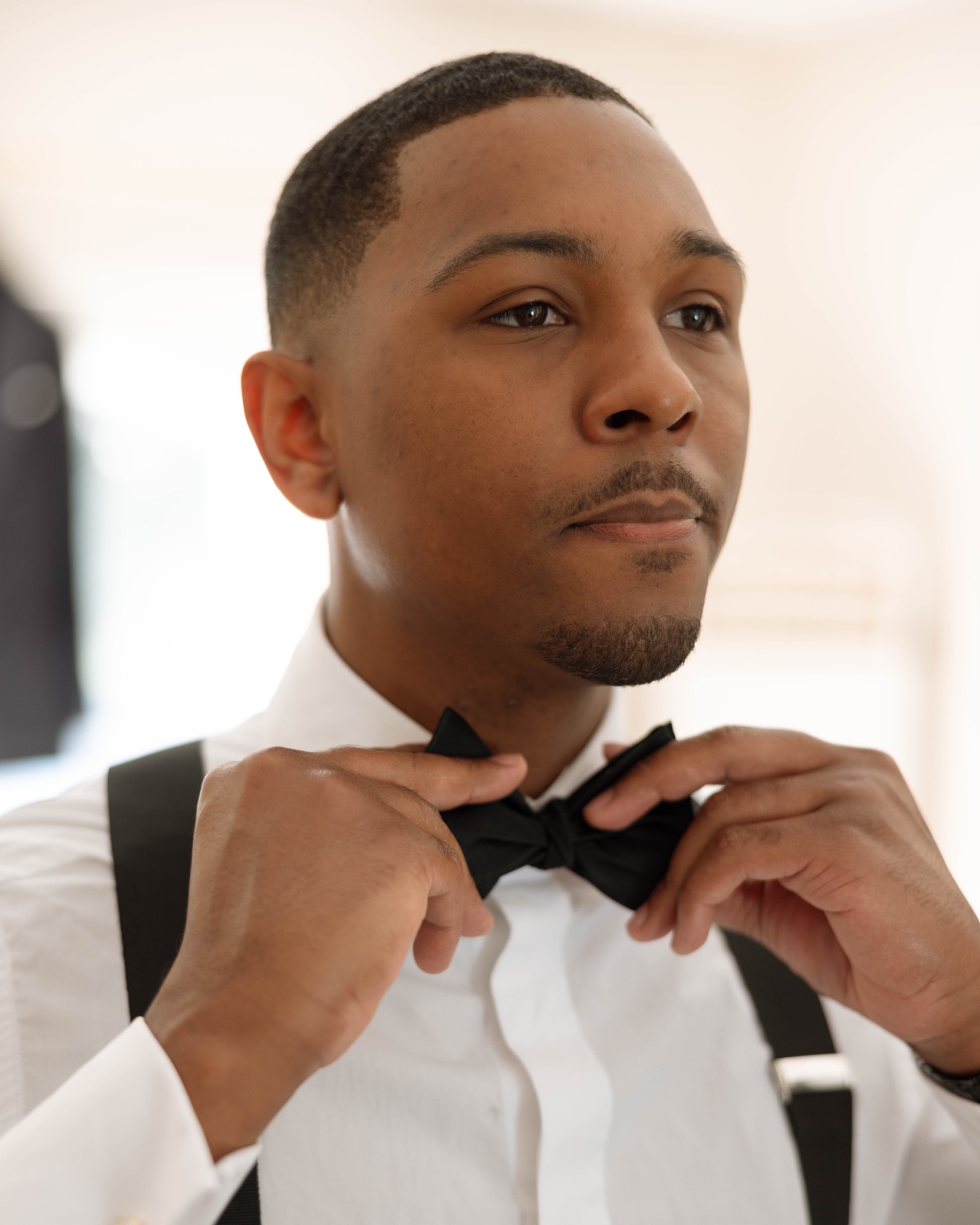 The groom fixing his bow tie