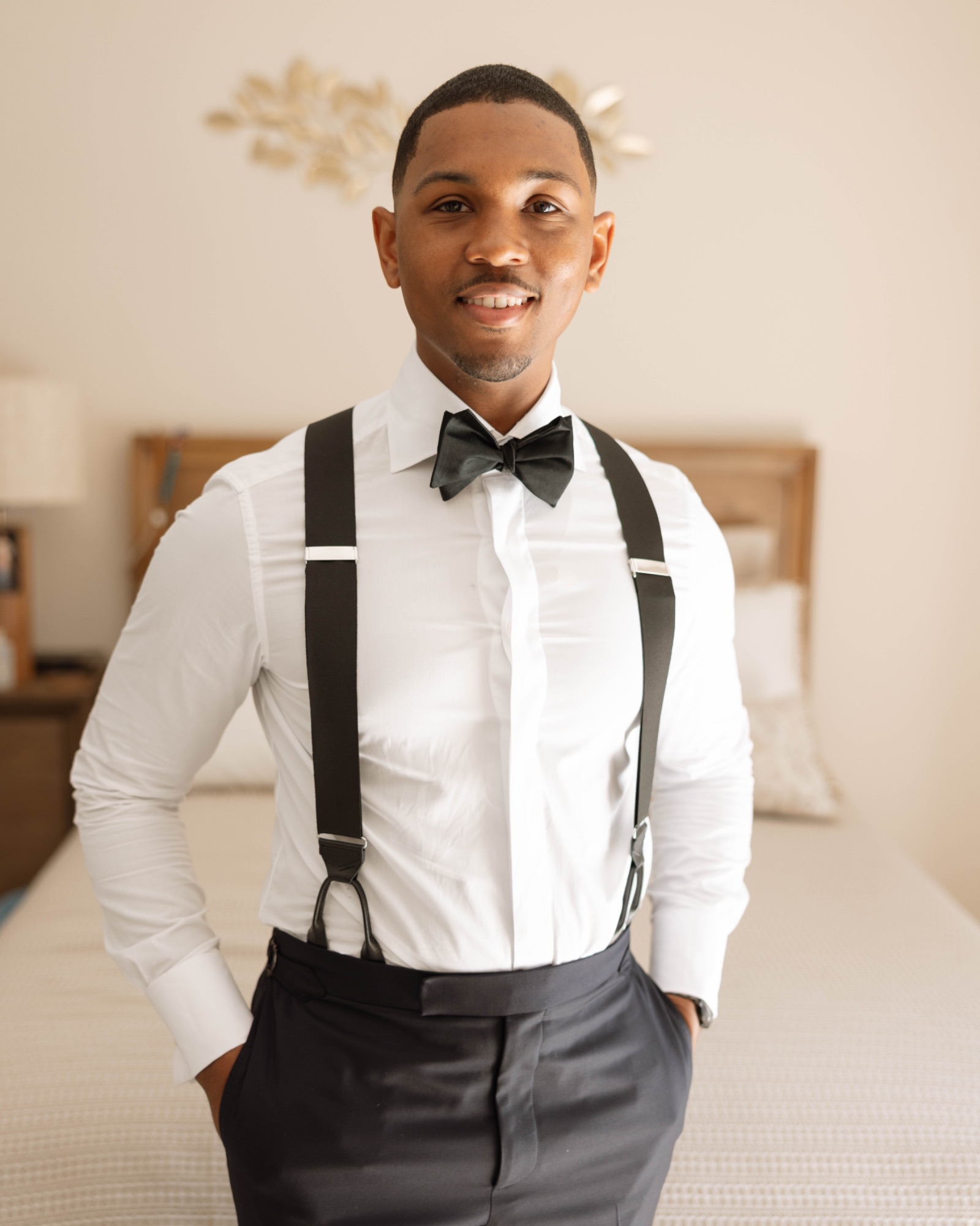 The groom in suspenders and bow tie, dressed and ready
