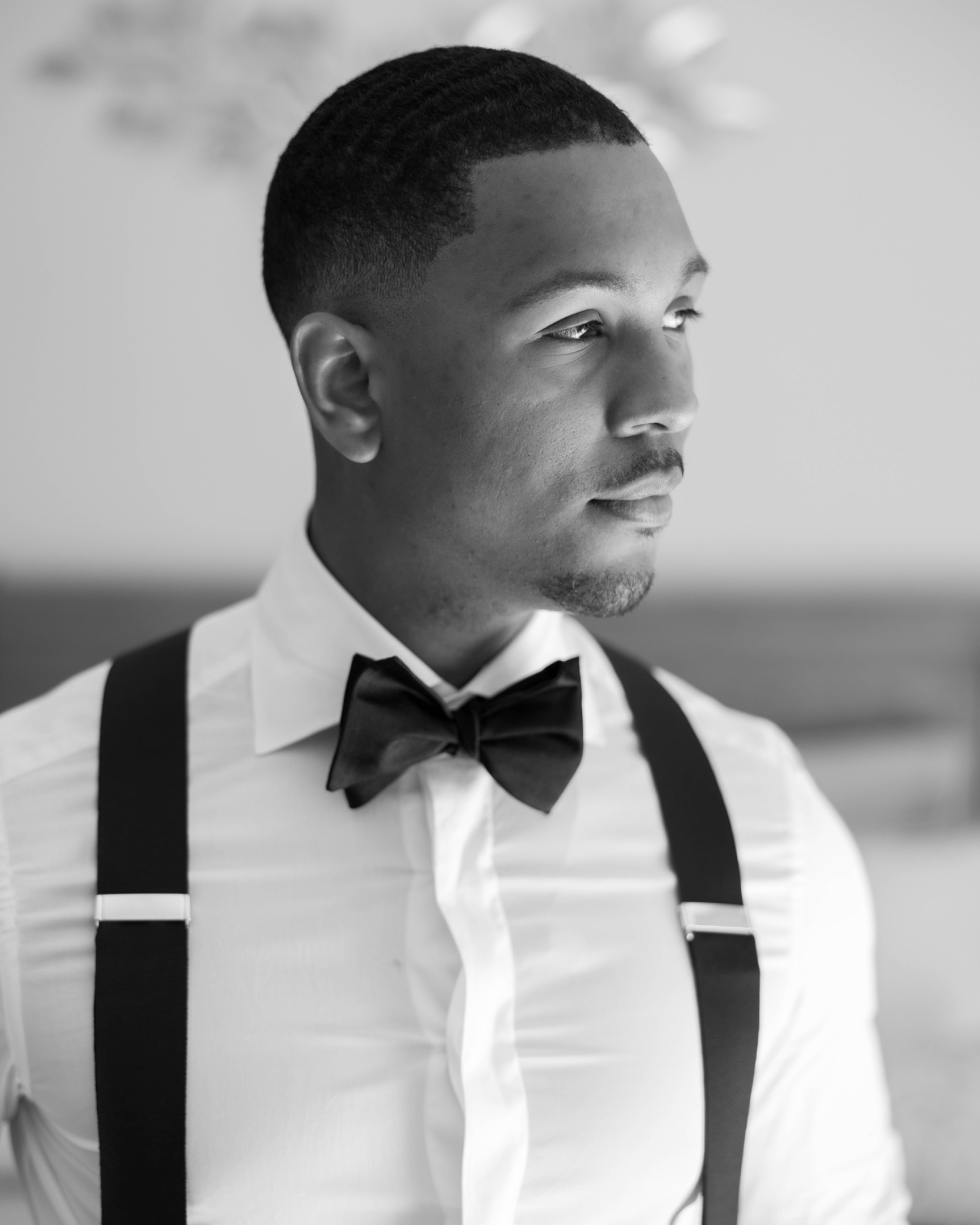 Profile of the groom in his bow tie and suspenders