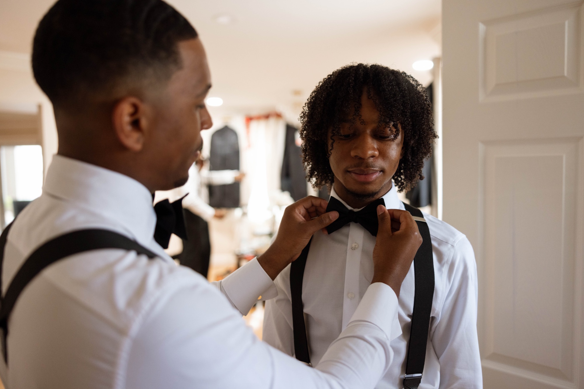 A groomsman straightening another's bow tie