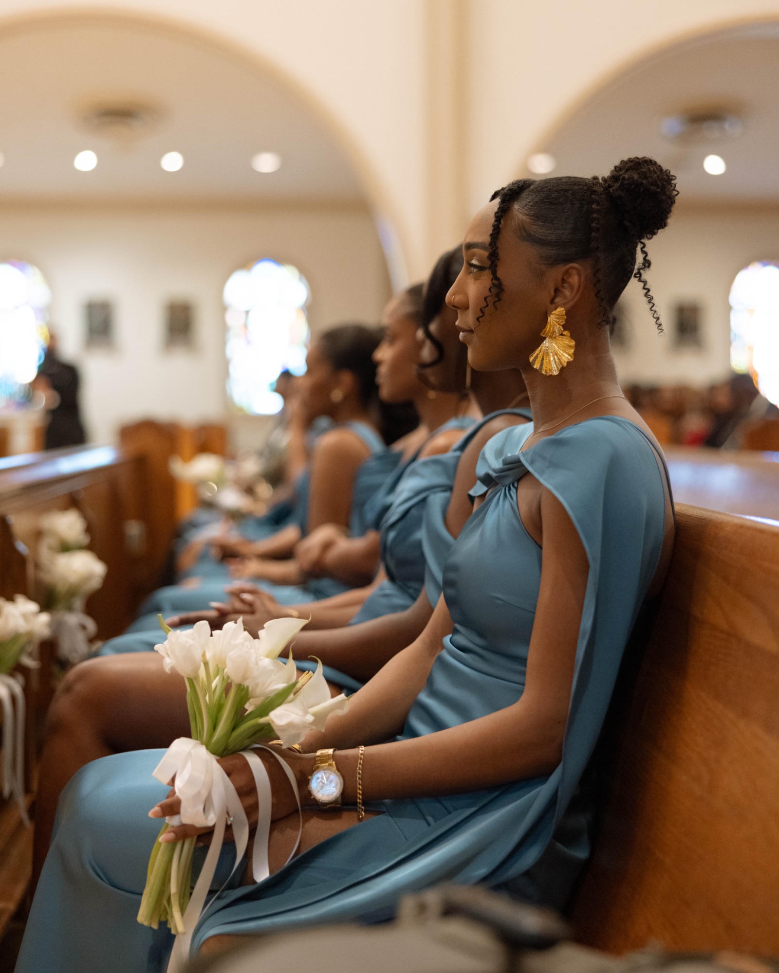 A bridesmaid in teal watching the ceremony from the pews