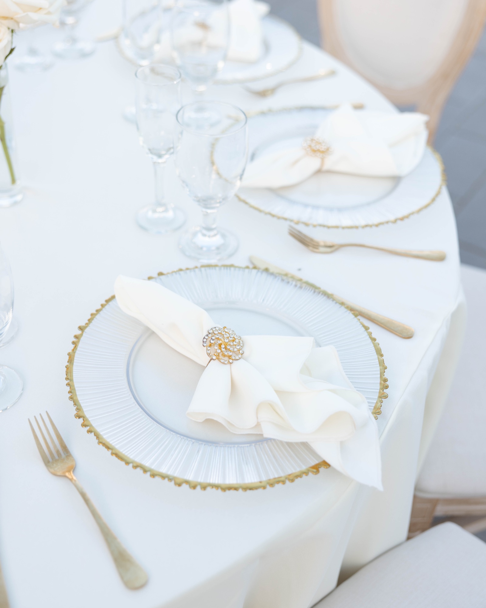 A place setting with gold flatware and a beaded charger