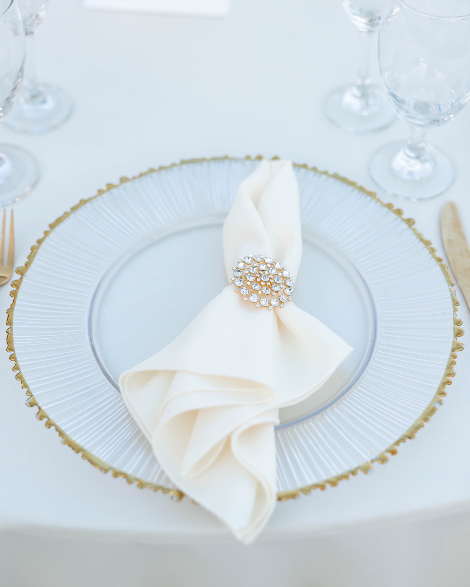 A napkin ring holding a folded napkin on a beaded charger