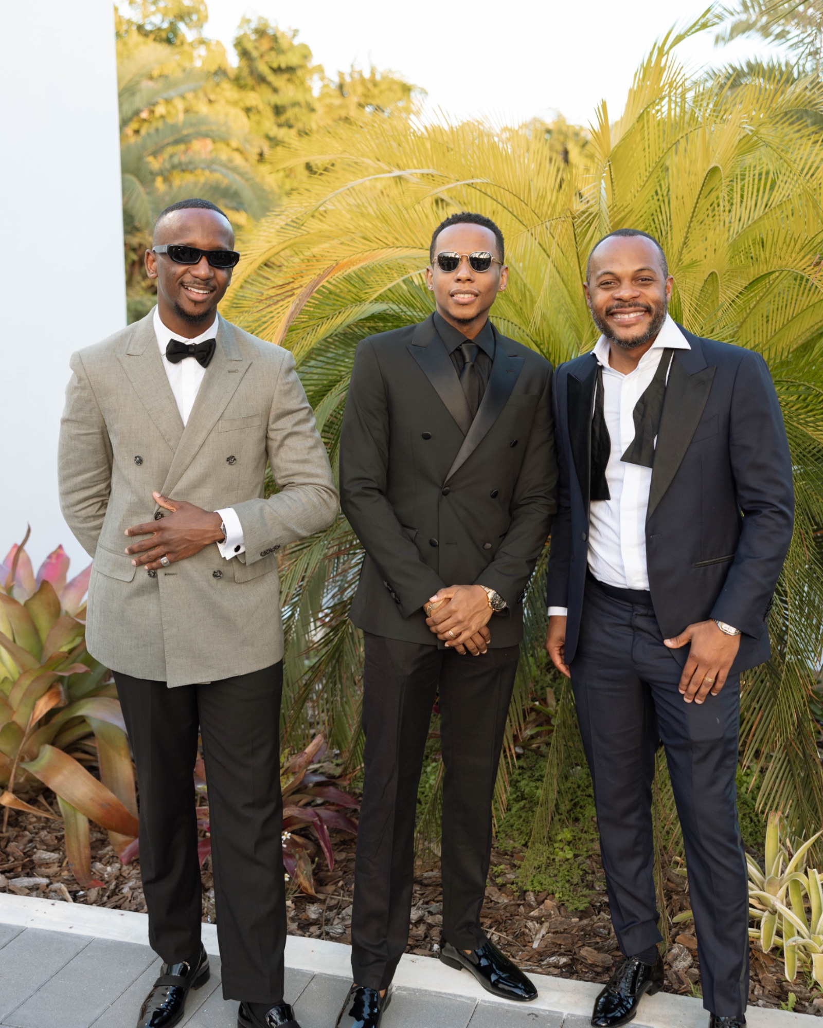 Three guests in black tie among the venue's planting