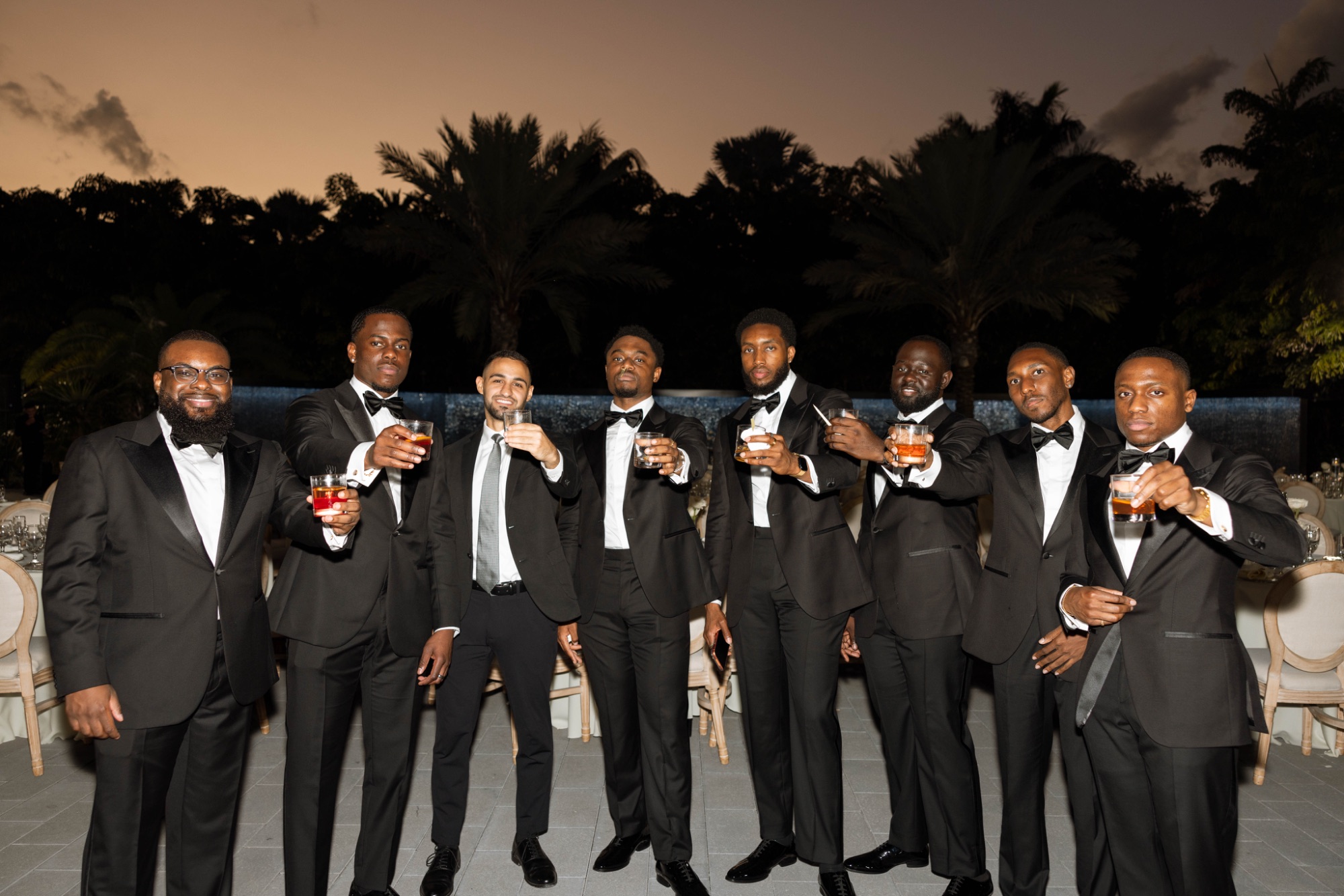 The groomsmen at night with their drinks raised