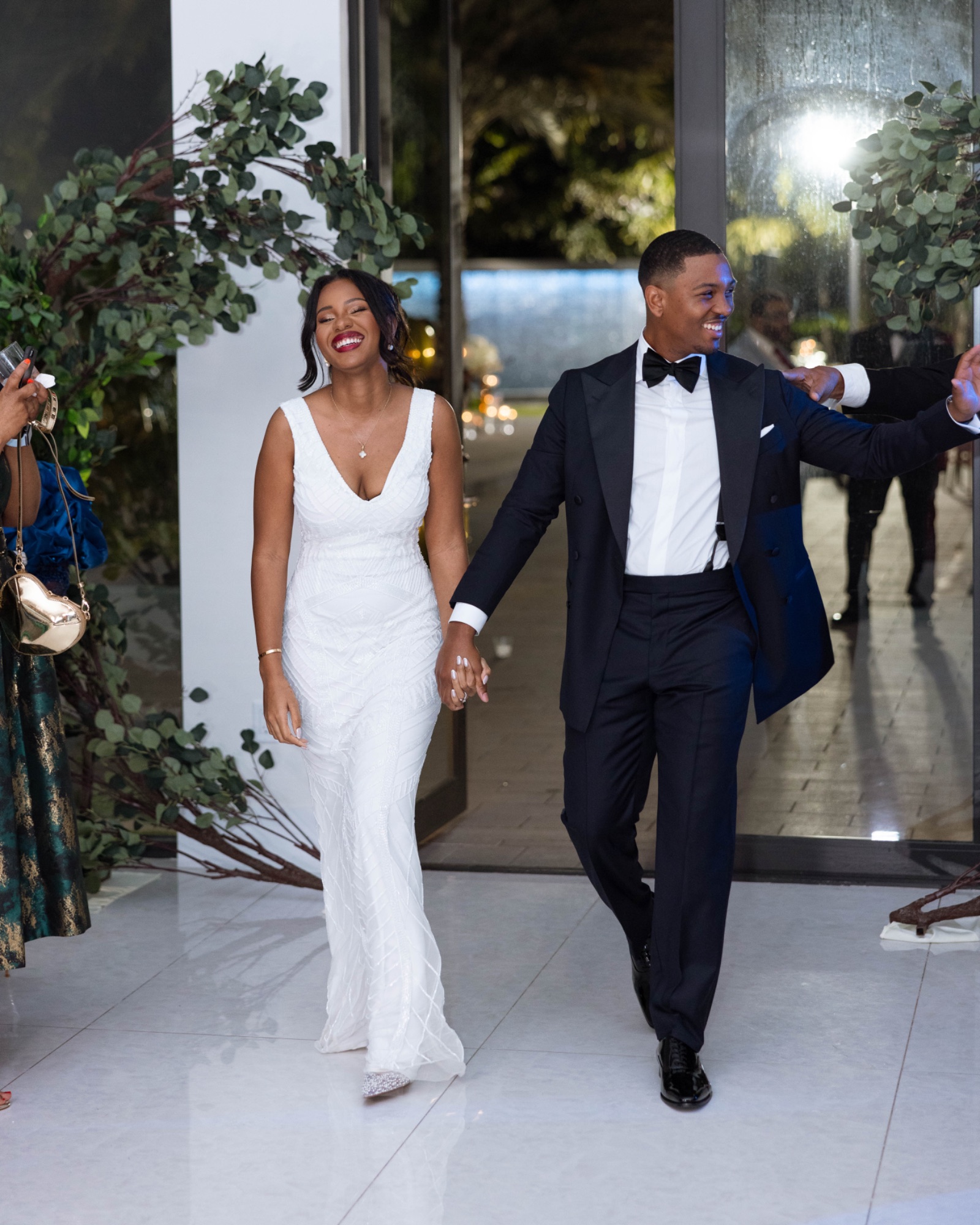 The couple walking into their reception, the bride in a fitted crepe gown