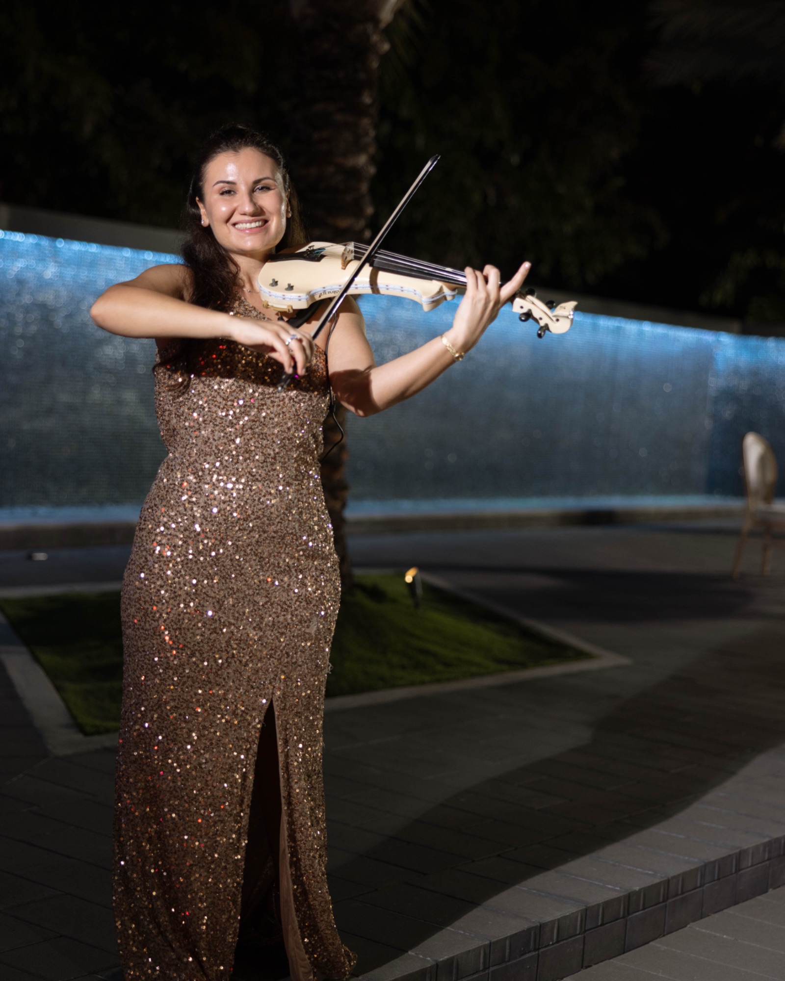 A violinist playing beside the illuminated waterfall