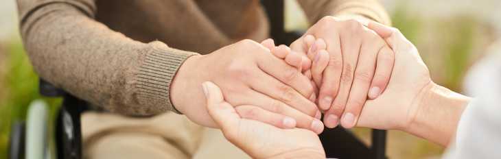 a picture two people holding hands, a support worker and a participant