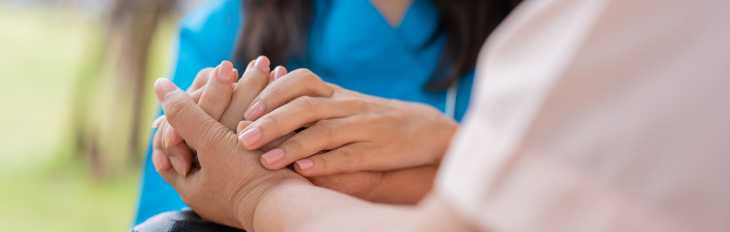 an image of a support coordinator holding the hand of her participant -- they cannot be seen in the image, only their hands