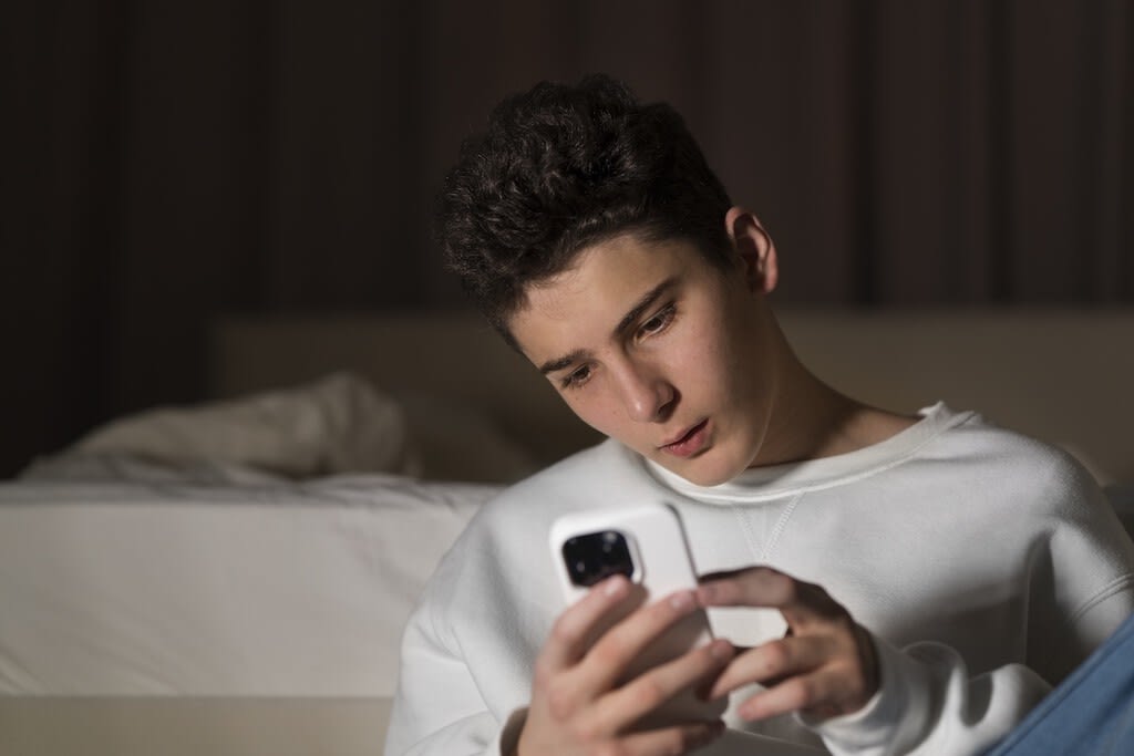 Joven con un smartphone en la mano, con múltiples aplicaciones abiertas en la pantalla, simbolizando la adicción a internet.