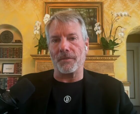 Michael Saylor, fundador de Strategy, revisando gráficos de Bitcoin en una oficina moderna.