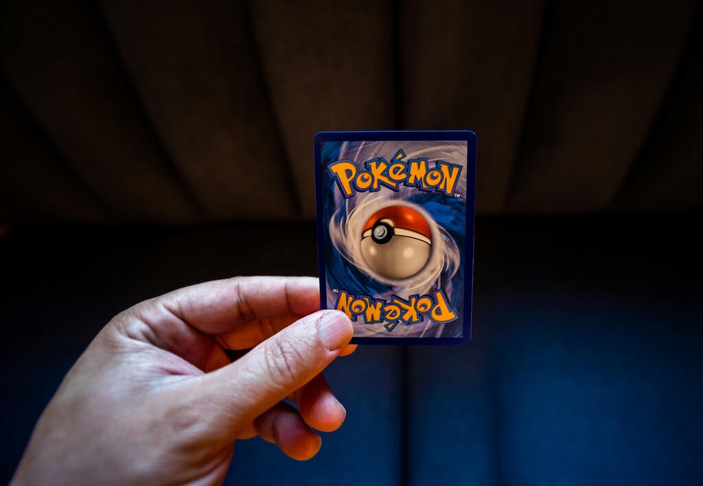 Tienda de cartas de Pokémon con un cartel de examen de conocimiento visible.