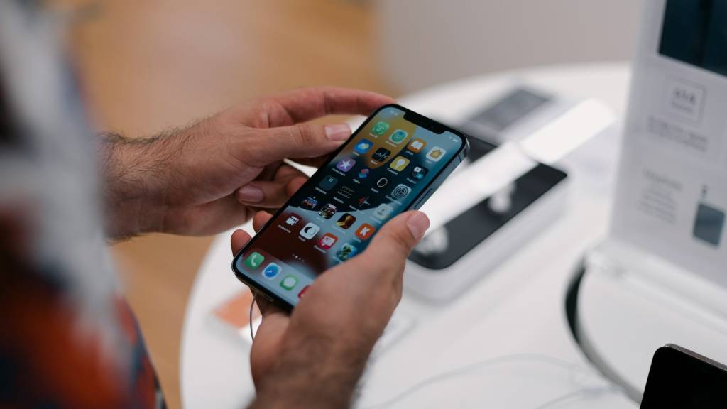 Imagen conceptual de un iPhone, MacBook y iPad dispuestos de forma moderna y minimalista sobre un fondo gris claro, representando la accesibilidad y el programa de arrendamiento de Apple.