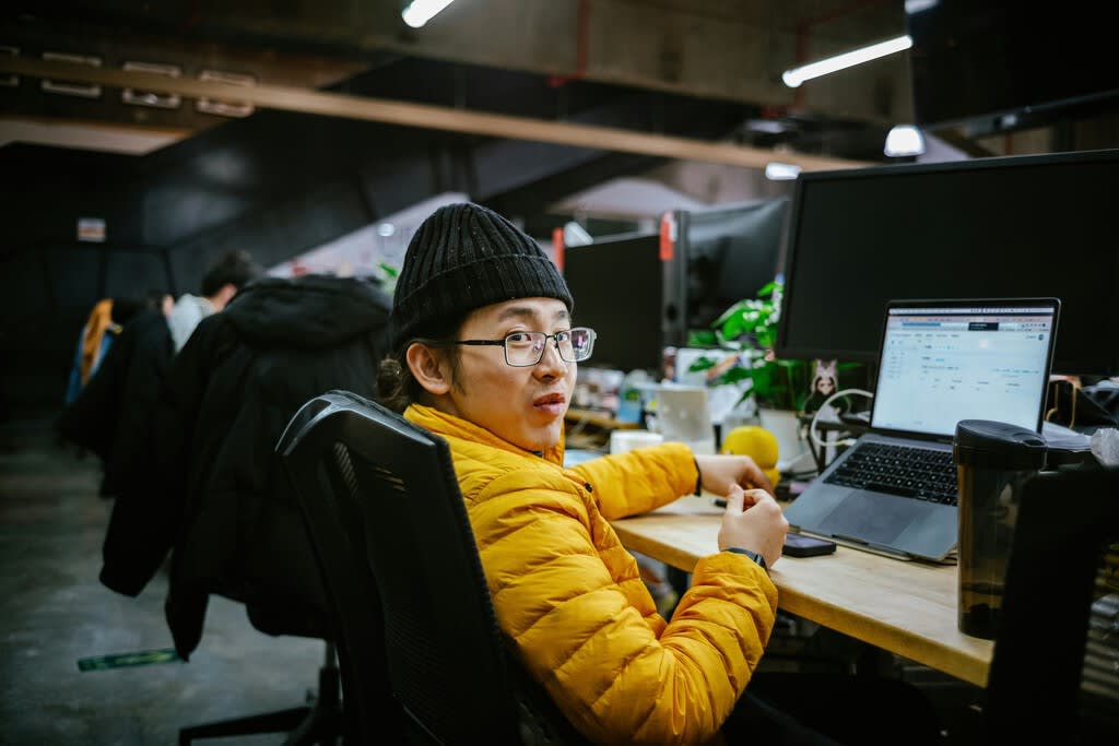 Un grupo de ingenieros chinos jóvenes y diversos trabajando en servidores de IA de alta tecnología en una oficina moderna en China.
