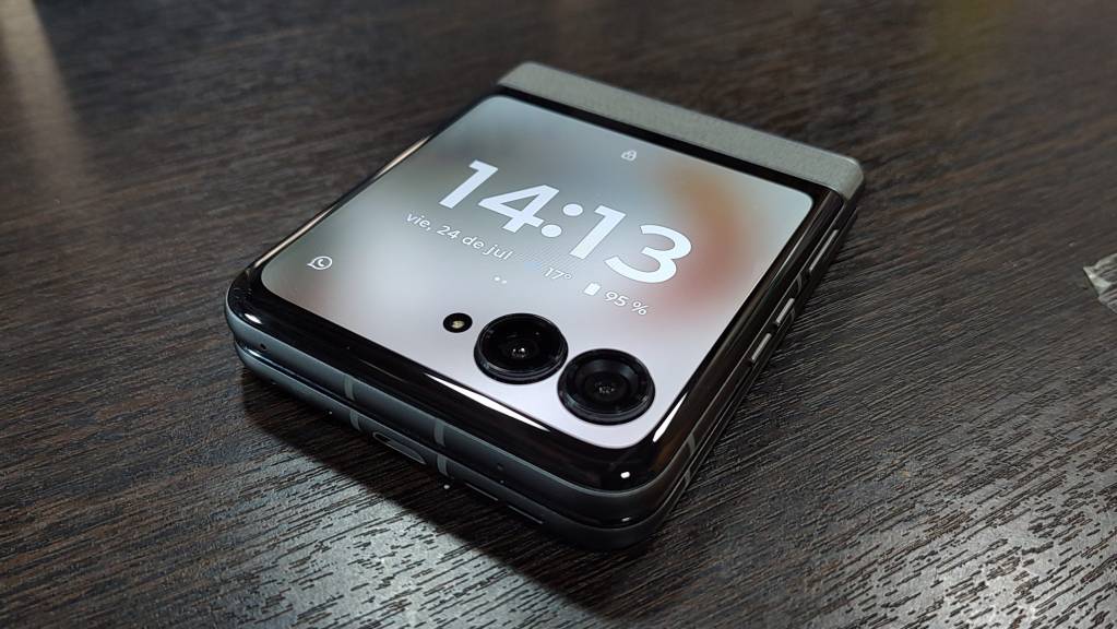Un smartphone plegable abierto sobre un escritorio moderno con accesorios tecnológicos.