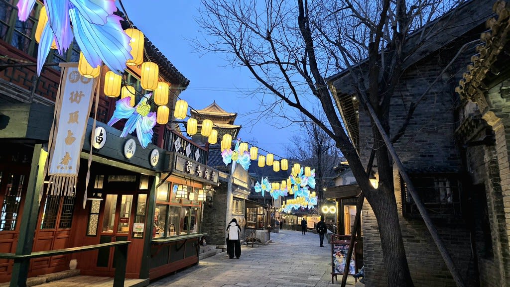 Réplica de un pueblo chino antiguo con canales y arquitectura tradicional iluminado por faroles por la noche.