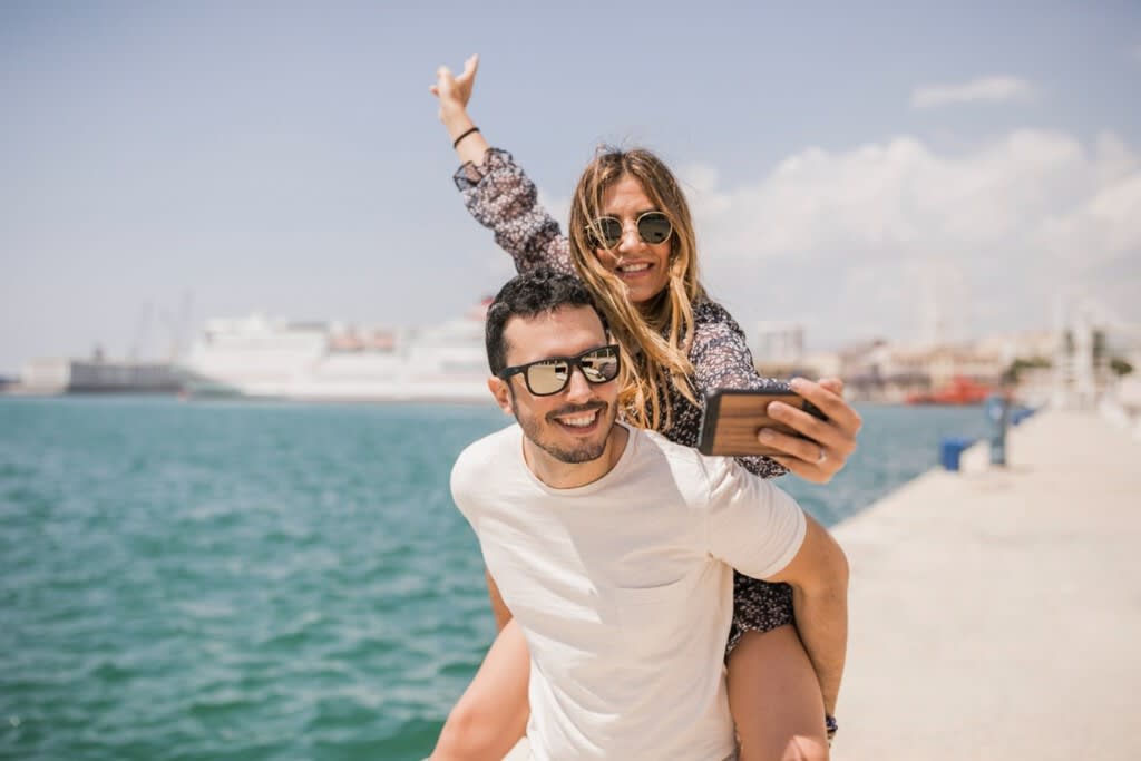 Una persona utilizando su smartphone con un mapa del mundo superpuesto, simbolizando la conectividad global.