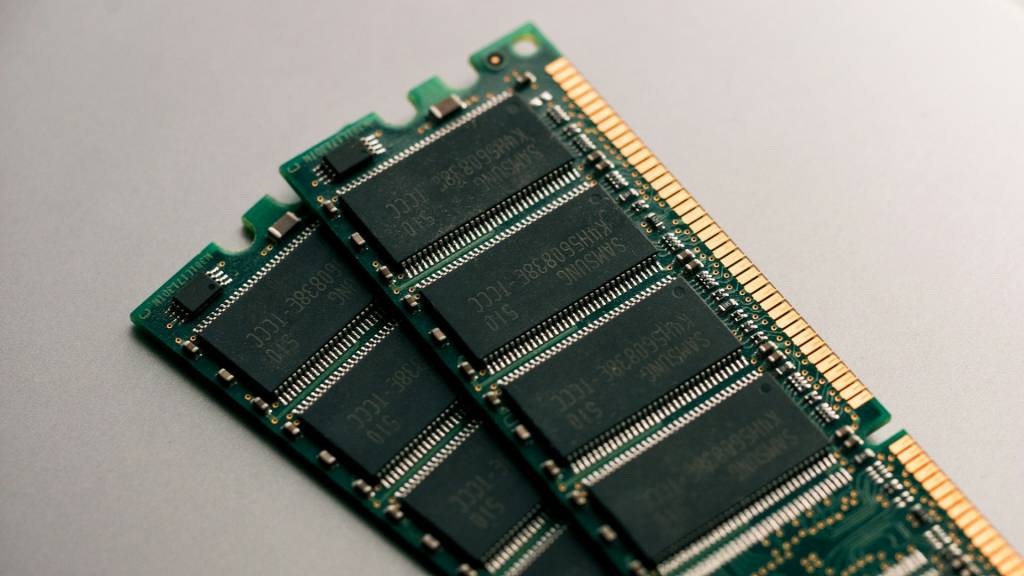 Un primer plano abstracto de chips de memoria RAM iluminados, simbolizando el aumento de precios impulsado por la IA.