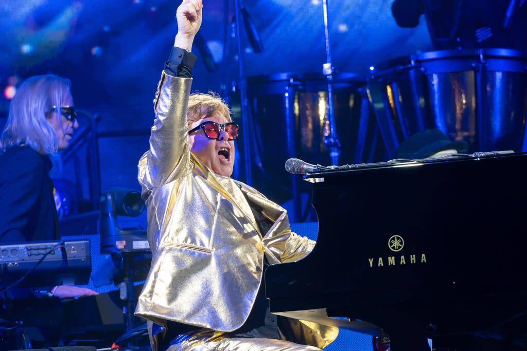 Elton John dirigiendo una orquesta con una batuta luminosa