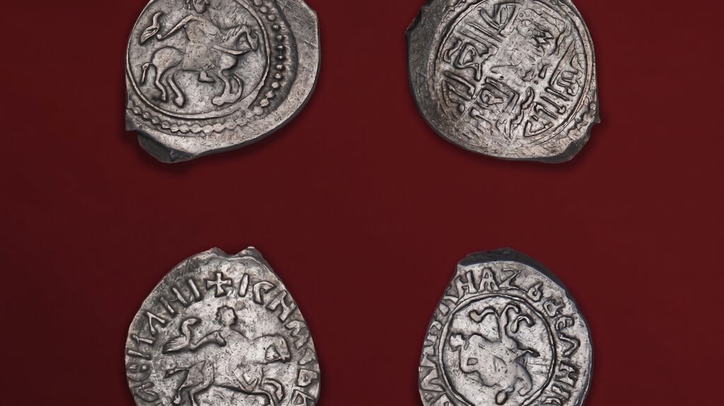 Un cántaro de cerámica antiguo desenterrado, lleno de monedas de plata antiguas.