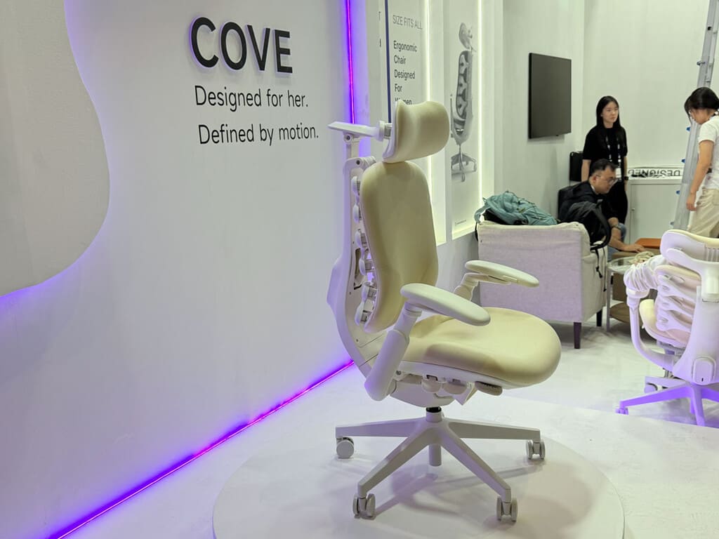 Una silla de oficina ergonómica de diseño futurista en color blanco, con un respaldo que recuerda a una columna vertebral, expuesta en un stand tecnológico.