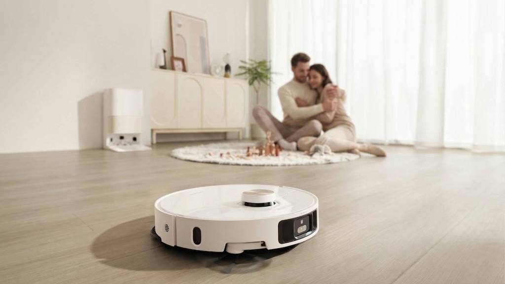 Un robot aspirador con una luz parpadeante, sugiriendo que está grabando, en un entorno doméstico moderno.
